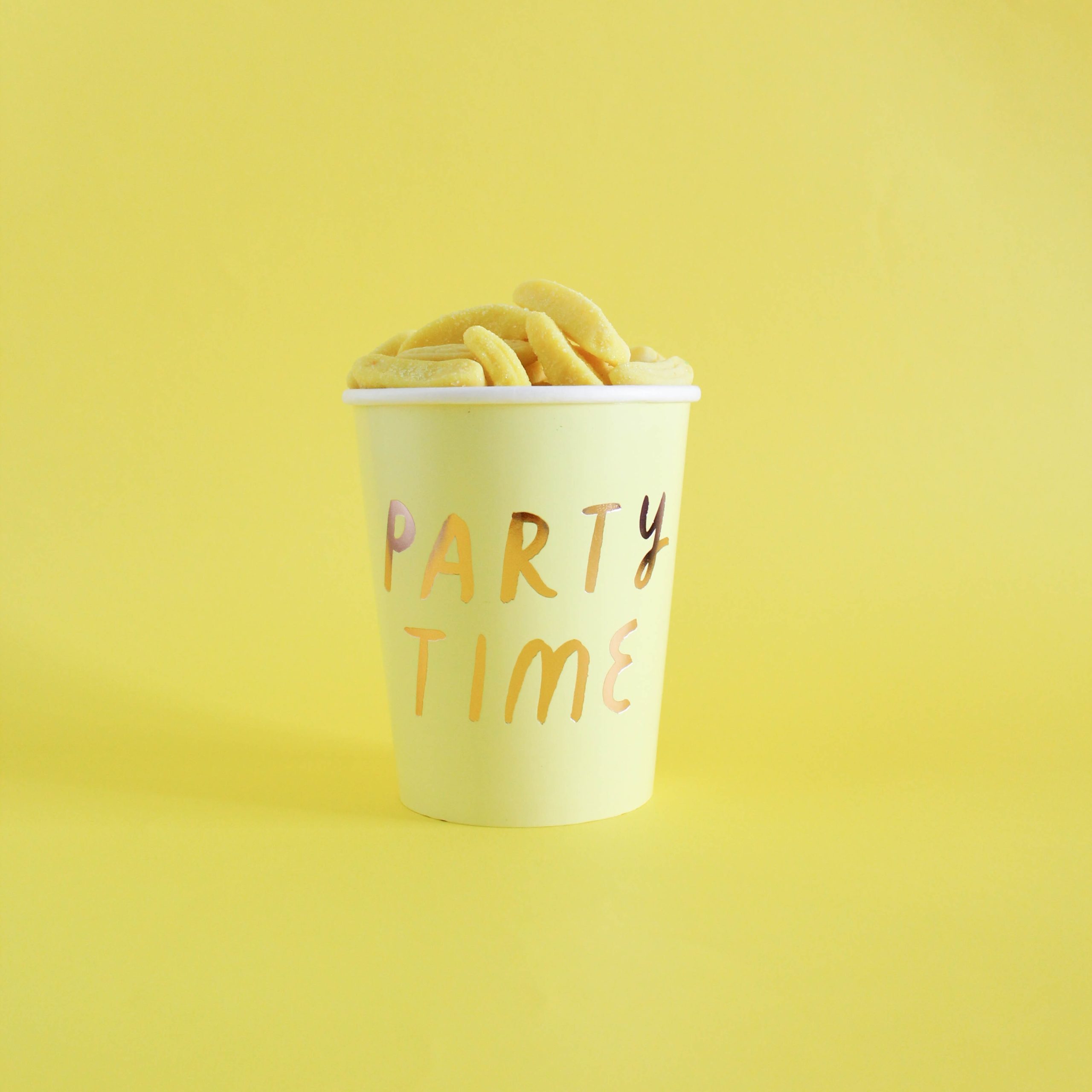 Yellow snacks in a paper cup that reads "Party Time" on a yellow background