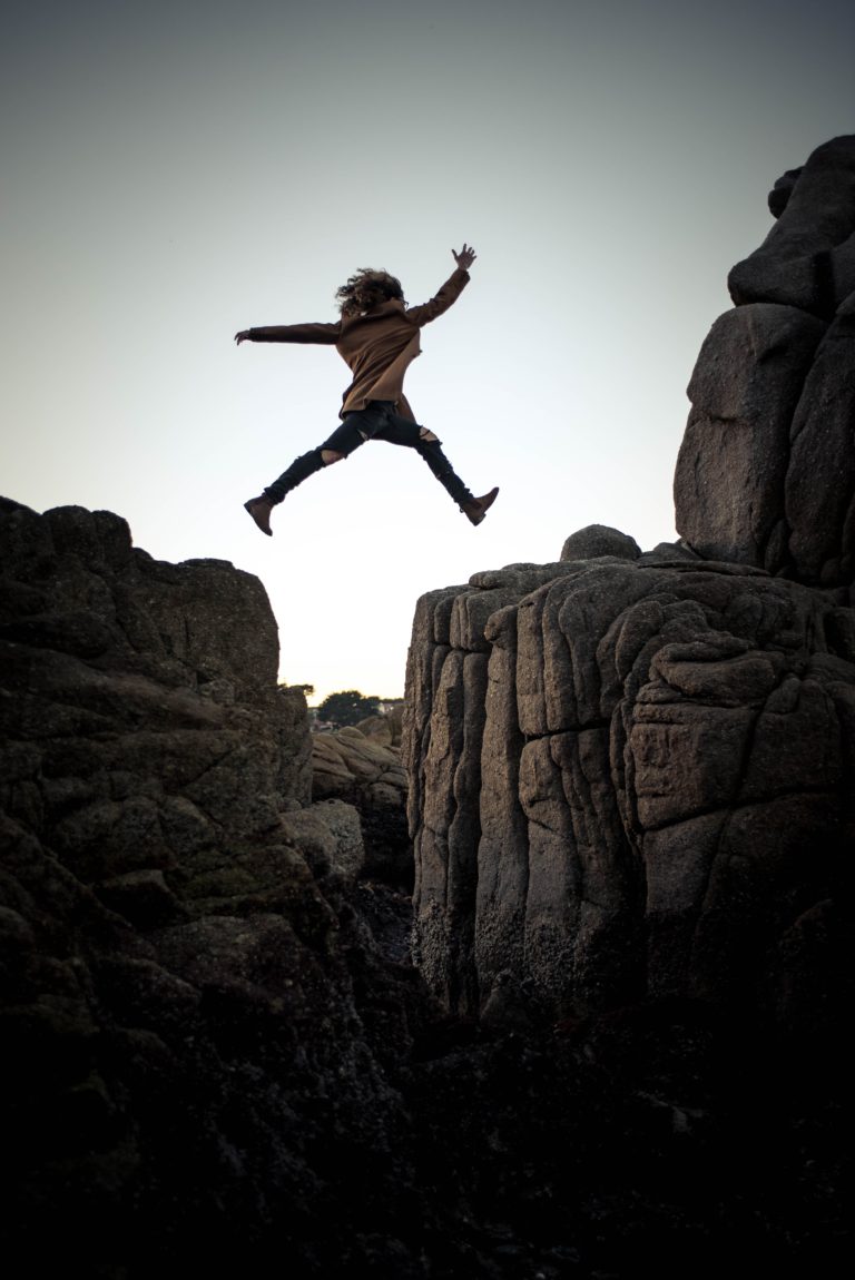 Woman leaping from one rock ridge to the next, arms outstretched