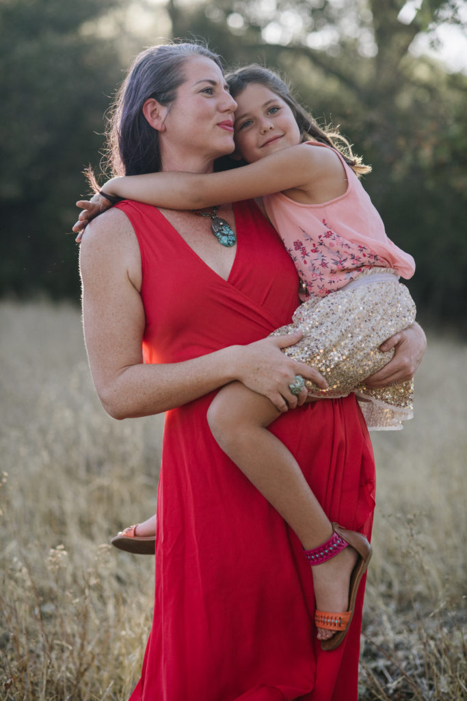 Woman in a red dress holding a child in a field