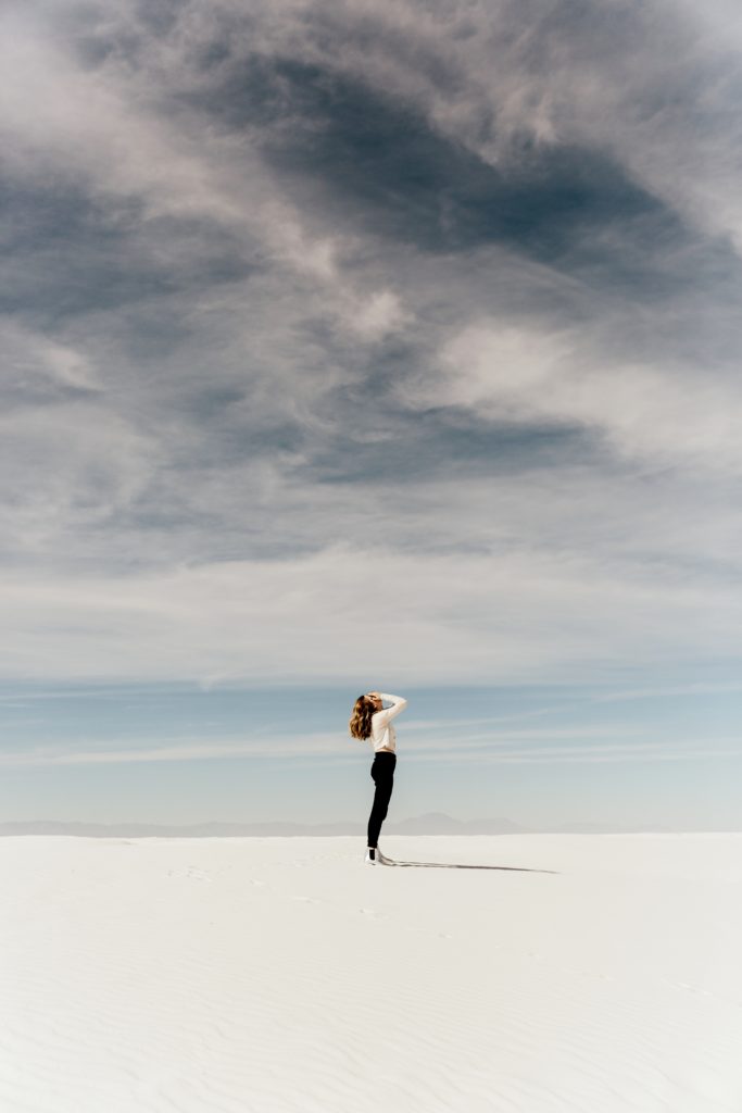 Woman holding her face alone in a dry lake bed