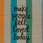 Art graffiti on a cinderblock wall "Make people feel loved today"